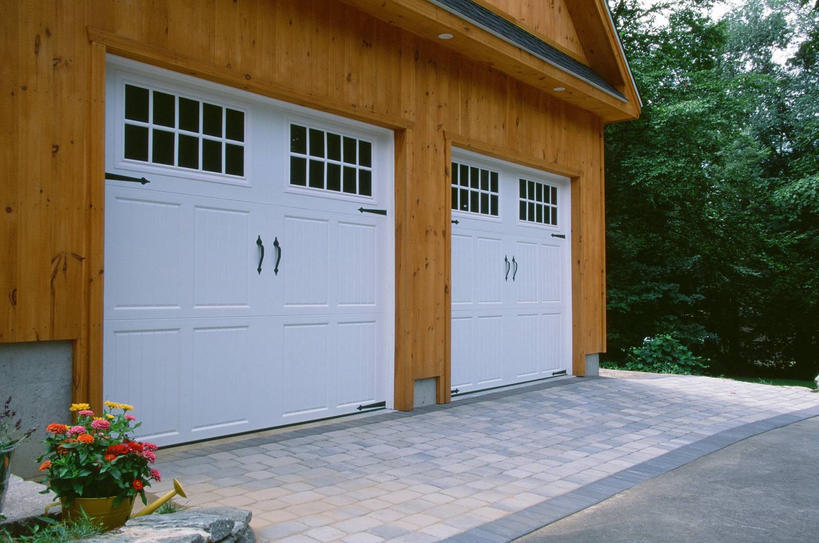 Shingled Eyebrow Roof with Recessed Lighting • Garage Doors • Paver Apron