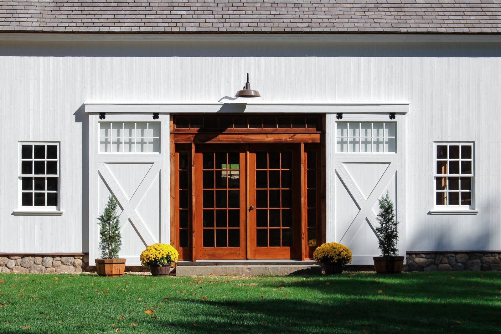 Split sliding barn doors open revealing wooden double doors with full view glass