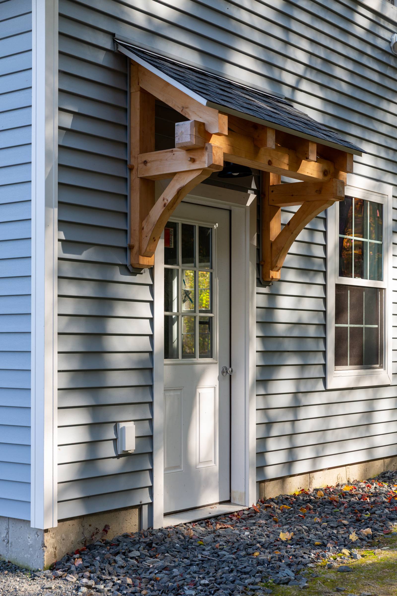 4' timber frame eyebrow roof over fiberglass entry door with half glass