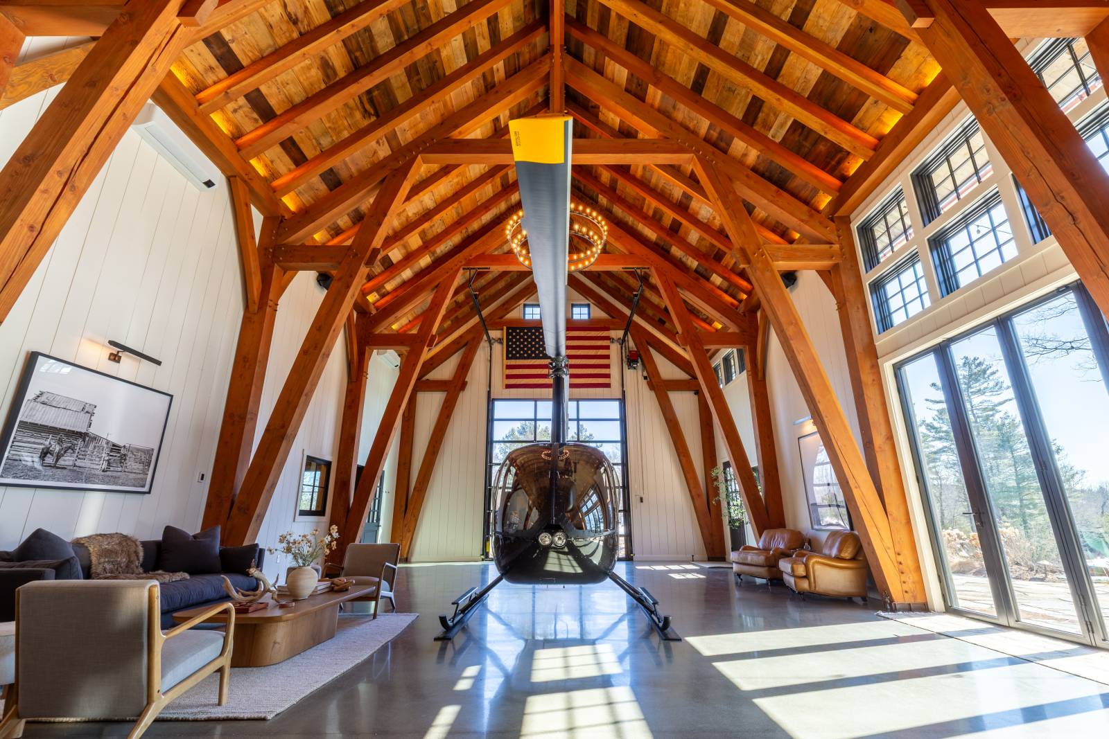 Robinson R44 helicopter inside this custom timber frame barn • timber frame barn post & beam custom hangar