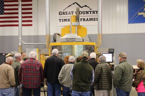 Sawdust flies around in the CNC machine as the crowd watches