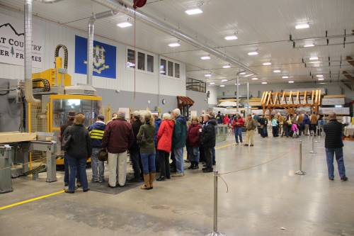 A group crowds the machine while another group learns about timber frame joinery