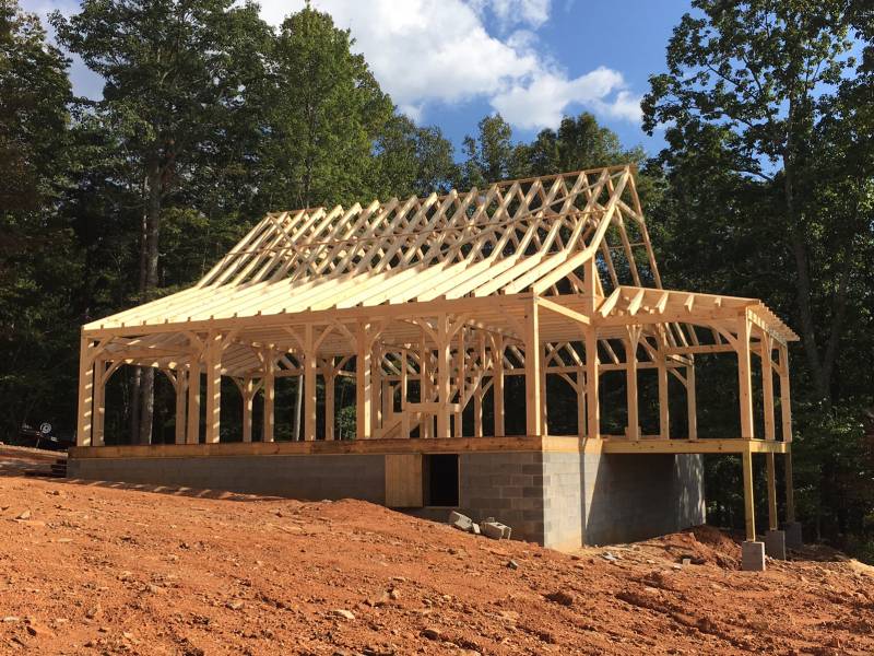 Side view of the barn home timber frame with porch overhang