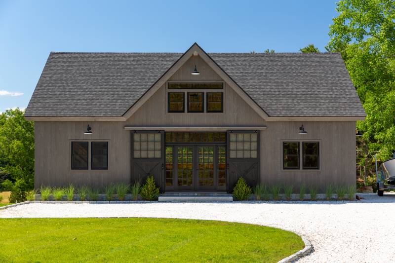 Front of the bank barn with reverse gable dormer and half glass sliding barn doors