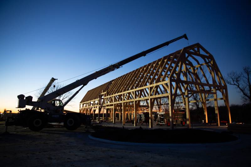 Crane reaches over the barn to set the lean-to rafters on the opposite side