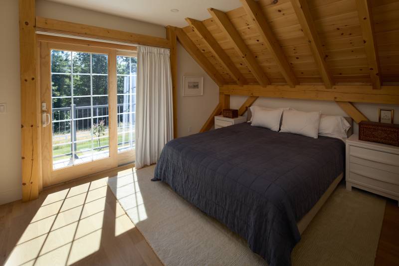 The main bedroom of the post & beam home with walkout to the balcony