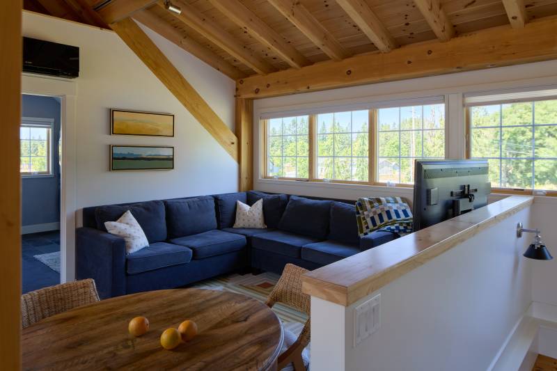 The living room in one of the 20' shed dormers, with stairs to lower level on the right • timber frame home barn house