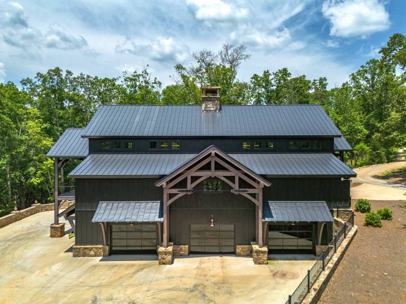 Gable portico, three overhead doors, and timber frame eyebrow roofs