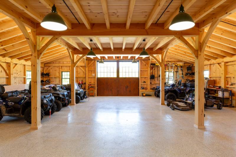 The front of both timber frame lean-tos is home to quads, off-road vehicles, and lawn equipment • post & beam barn
