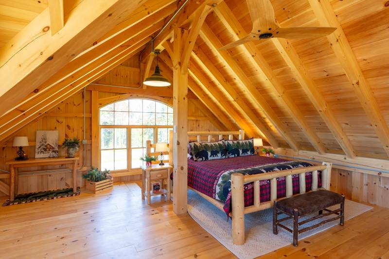 A bed in the loft • The rustic bed frame matches the post & beam interior
