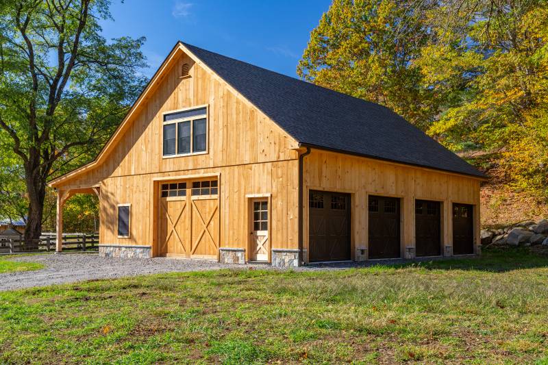 Four overhead doors line the right side of the timber frame barn