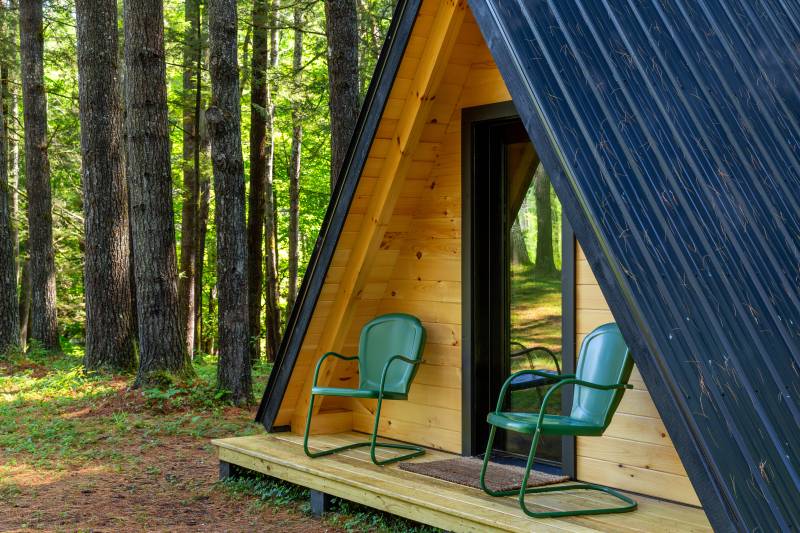 Two chairs sit on the A-Frame Cabin’s covered porch