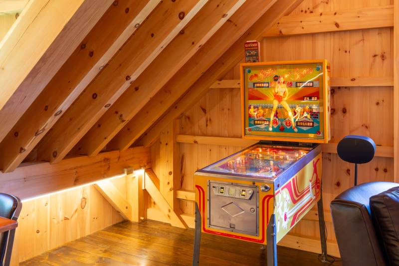 Strip lighting illuminates the knee-wall • Pinball machine