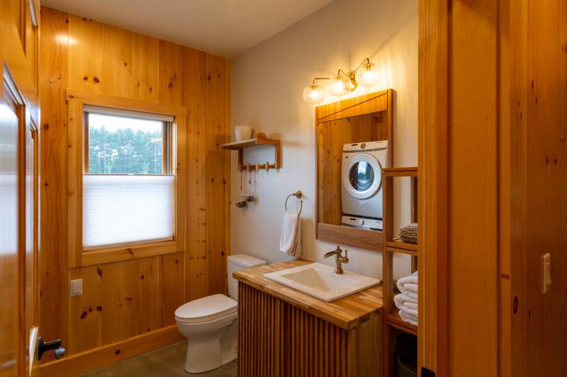 A full bathroom with laundry space within the barn’s guest area