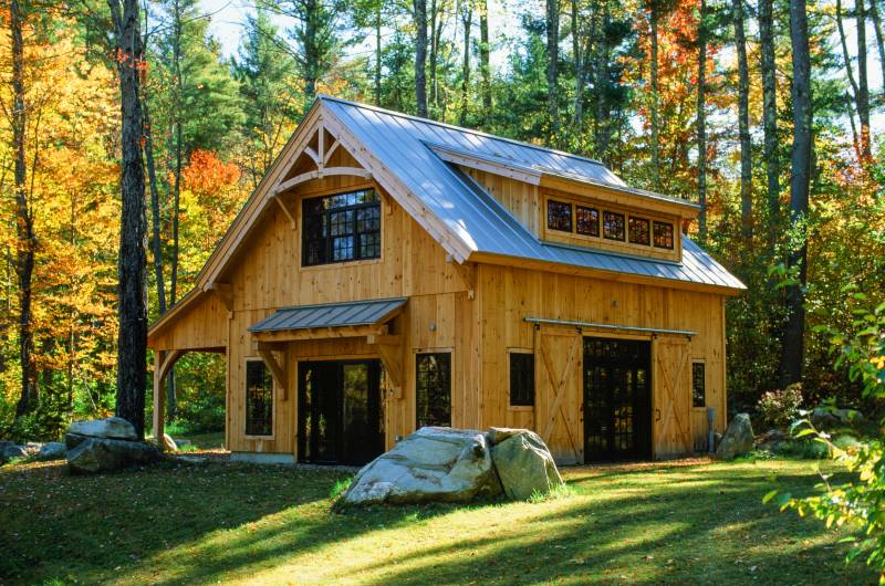 Timber truss accent with show rafter • Timber frame eyebrow roof over sliding door • Carriage Barn with Vermont fall foliage