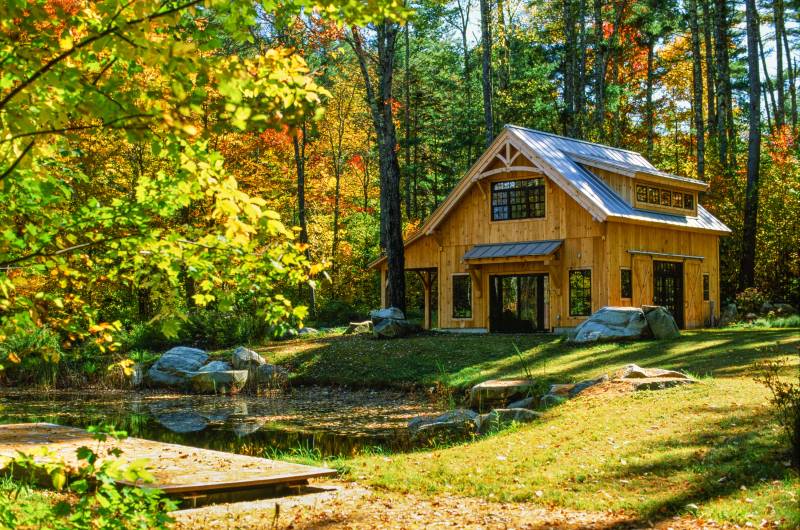 The barn sits on the shore of a small pond, surrounded by the colors of fall in Vermont