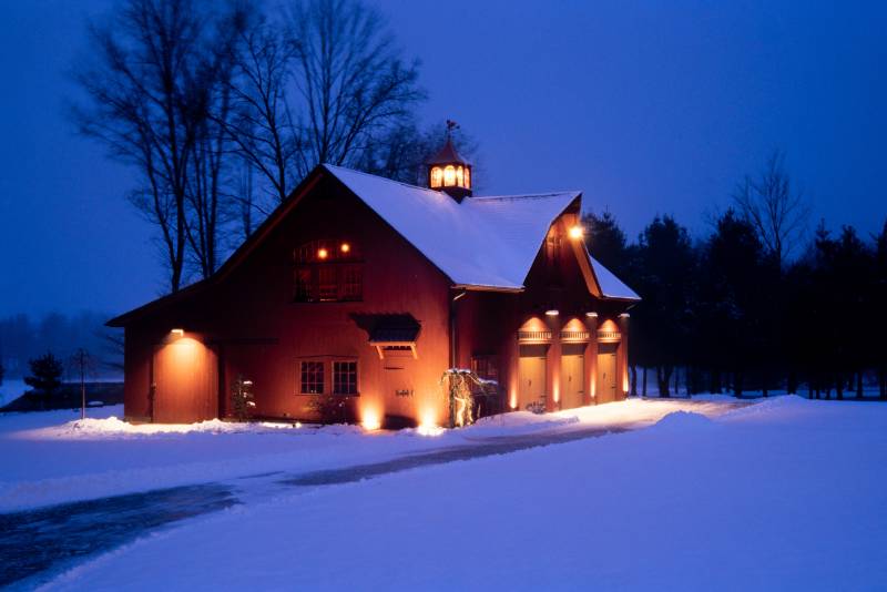 The post & beam barn, illuminated on a snowy night