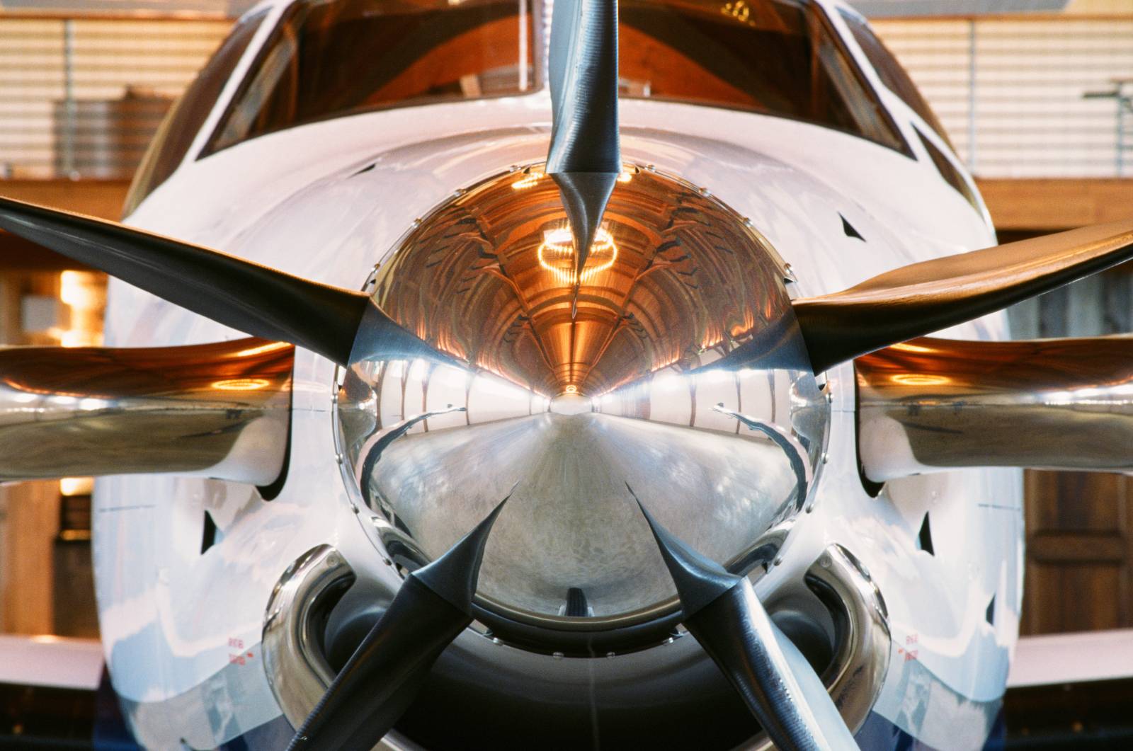 The timber frame airplane hangar, as seen in the reflection on the Pilatus PC-12 NGX propeller