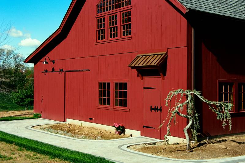 Side of barn featuring 3' entry door with oak latch & strap hinges and custom timber frame eyebrow roof with copper standing seam