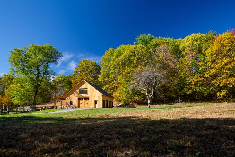 The post & beam barn surrounded by fields & fall foliage