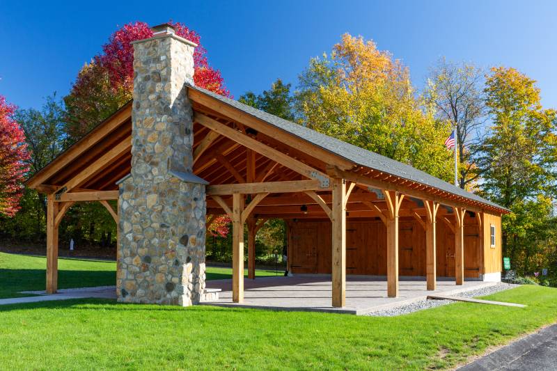The pavilion has a stone fireplace on one side and enclosed storage space on the other