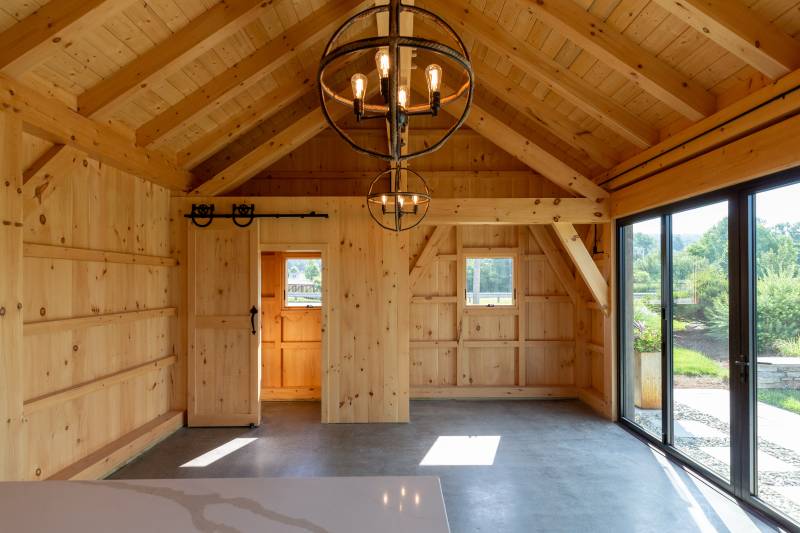 The right side of the timber frame pool house has an enclosed bathroom and space for entertainment