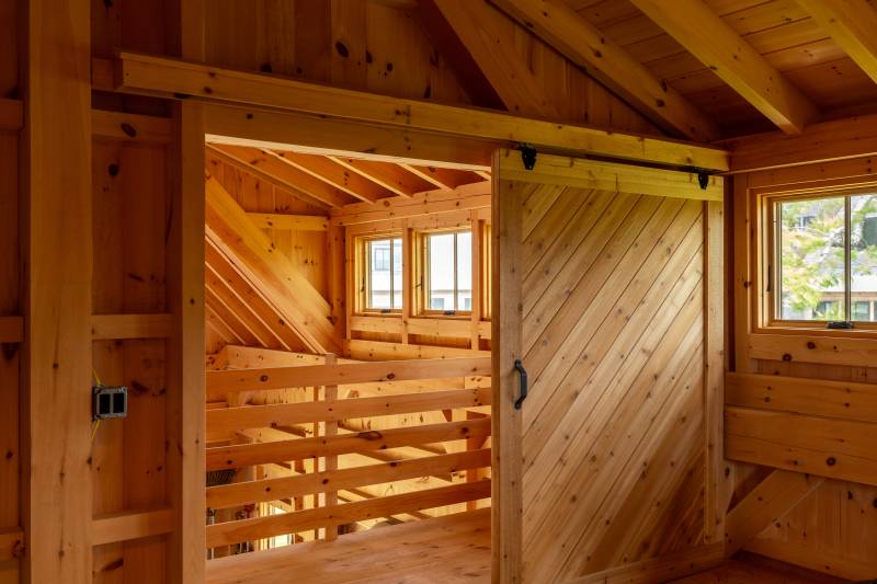 A split sliding door with herringbone pattern separates the loft from the rest of the barn