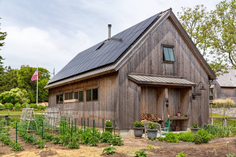 A large garden wraps around the side of the timber frame barn